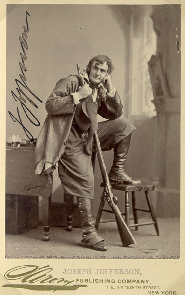 black and white photo of Joseph Jefferson in costume as Rip Van Winkle leaning on a stool with a rifle, he is clean shaven