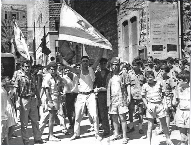 black and white photo of a Young man waving an Israeli flag stained with blood and hand lettered