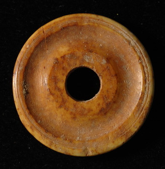 a circular brown disk with a hole in the center and a concave indent between the inner hole and outer rim