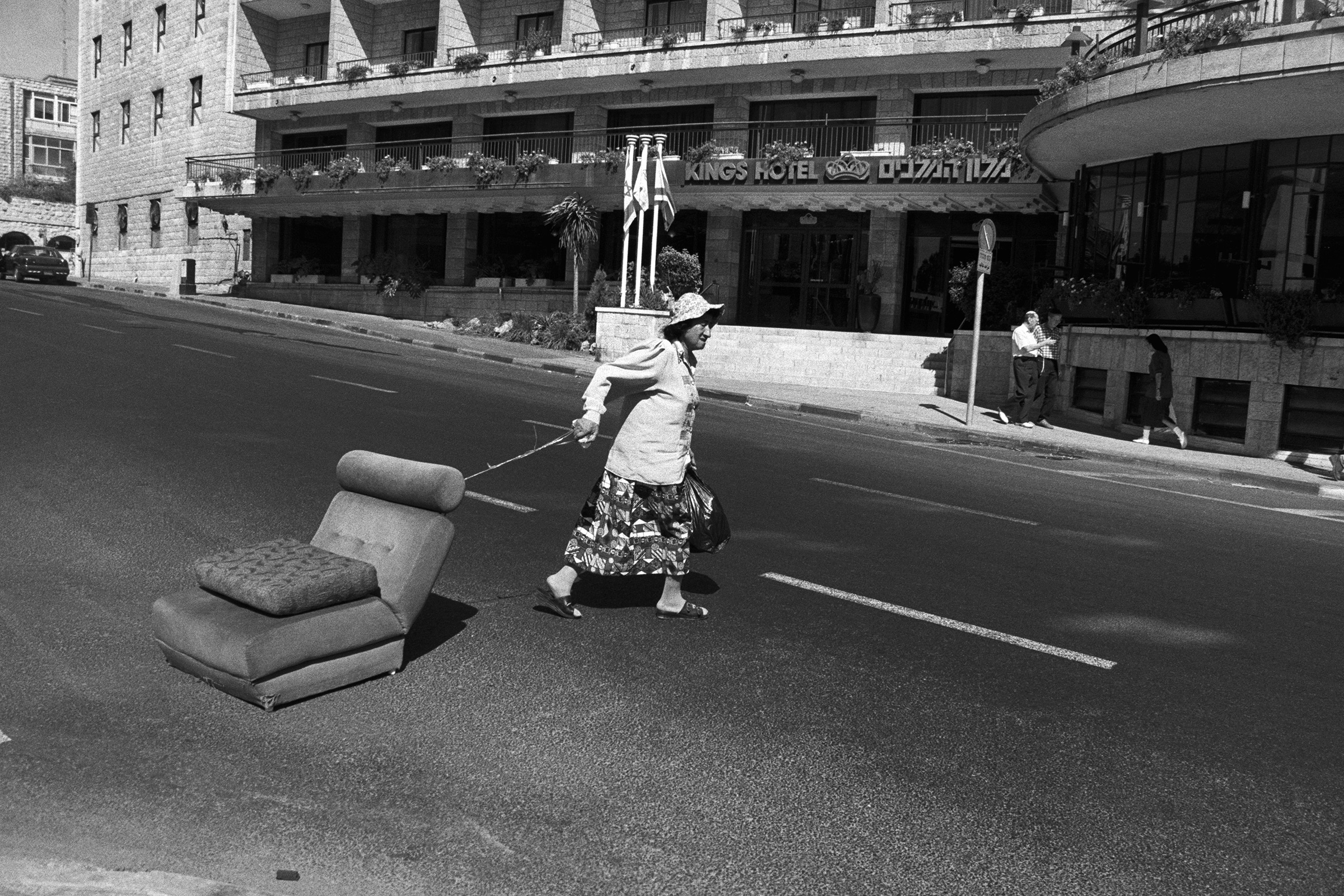 black and white photograph of a Woman dragging a couch across King George Street in Jerusalem