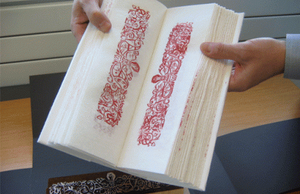 Hands holding book open with printed decorative borders