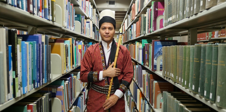 Juan Castrillón holding ney in library stacks