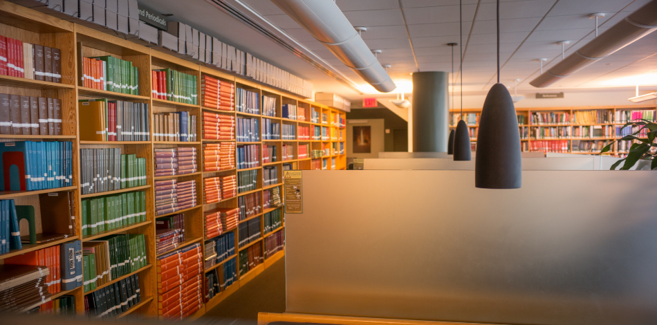 Photo looking down a line of desks with a bookshelf on the left-hand wall, filled with colorful books.
