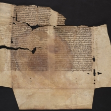Manuscript fragment showing folds from being in a bookbinding and other damage from loss of the parchment.