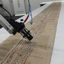 Camera scanning unrolled manuscript of genealogical roll.