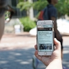 Individual holding mobile phone on Penn's campus with NYTimes app visible on screen