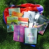 A selection of featured books lay on a backpack in the grass.